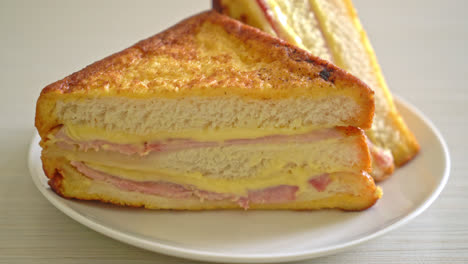 Sándwich de jamón y queso casero en la placa blanca.