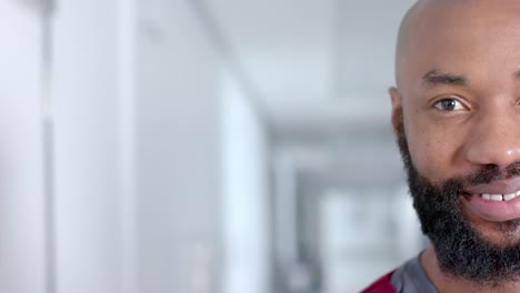 Portrait-of-happy-african-american-male-doctor-smiling-in-corridor,-copy-space,-slow-motion