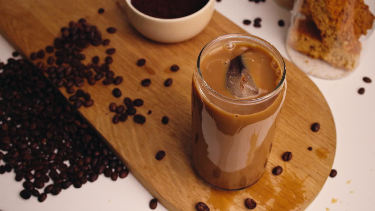 Caffè freddo mescolato con una cannuccia su una tavola di legno