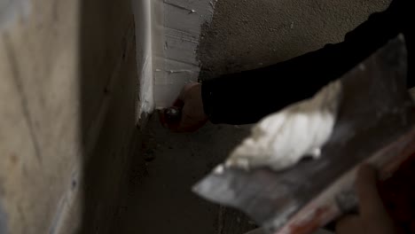 man applying interior masonry stucco to block wall with a putty knife spatula, close up shot