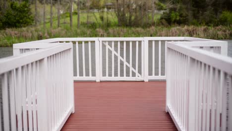 static shot of the balcony with white fense and pink ground by the pond