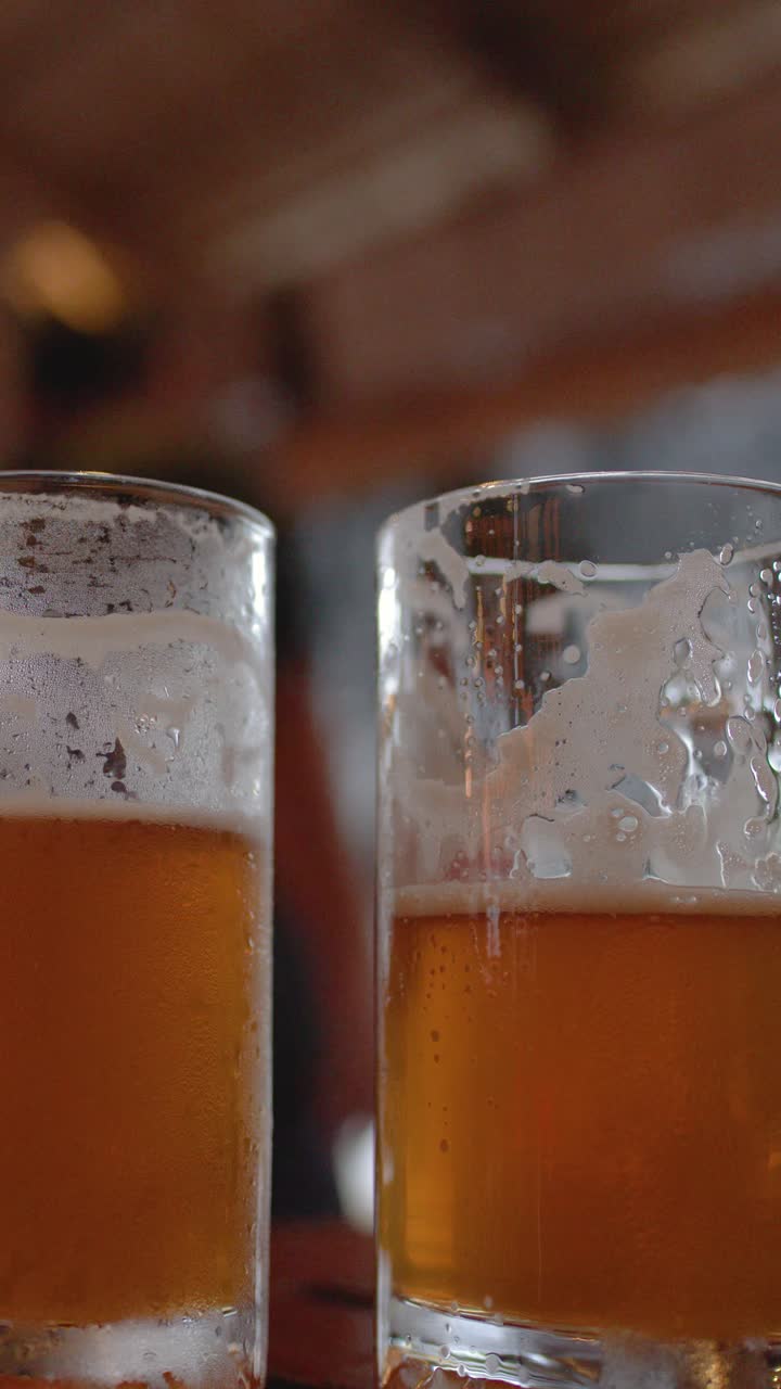 Primo piano statico di bicchieri di birra ambrata con condensa su un tavolo all'aperto di notte