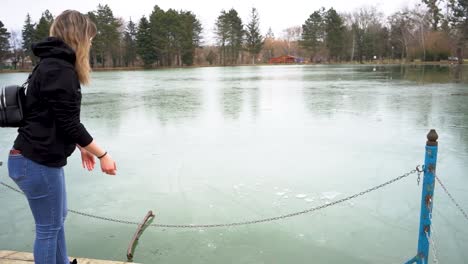 Mujer-Joven-Lanzando-Un-Bloque-De-Hielo-En-Un-Lago-Congelado