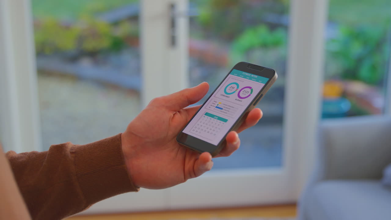 primer plano de un hombre en casa con el teléfono mirando una aplicación de seguimiento de fitness