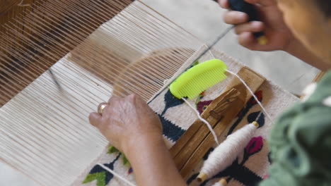 A-woman-hand-weaving-a-tapestry-on-a-loom-in-Oaxaca,-Mexico