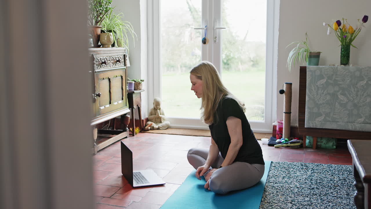 Woman practicing yoga at home during a video call