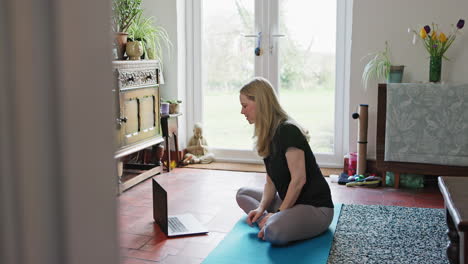 woman practicing yoga at home during a video call
