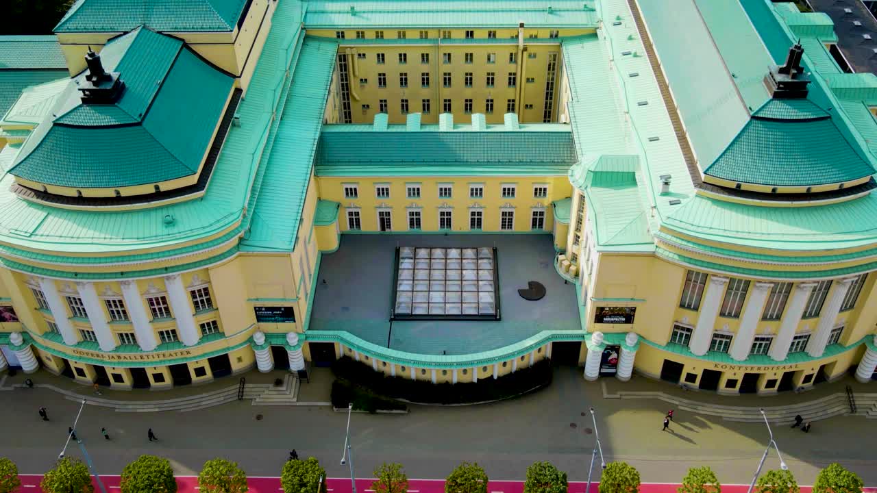 Gorgeous aerial drone hyperlapse of a large opera and theatre building in Tallinn central city during a sunny day. Surronded by medieval and modern buildings and baltic sea visible in the horizon