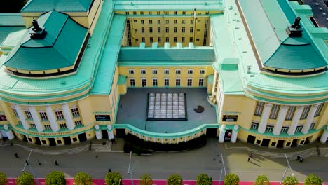 gorgeous aerial drone hyperlapse of a large opera and theatre building in tallinn central city during a sunny day. surronded by medieval and modern buildings and baltic sea visible in the horizon