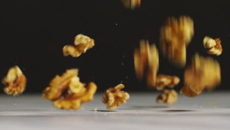 disparo de cerca de nueces cayendo sobre la superficie de mármol contra el fondo de estudio negro disparado en cámara lenta 1