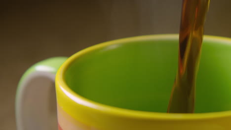 close up, black coffee is poured into a colourful mug, left steaming