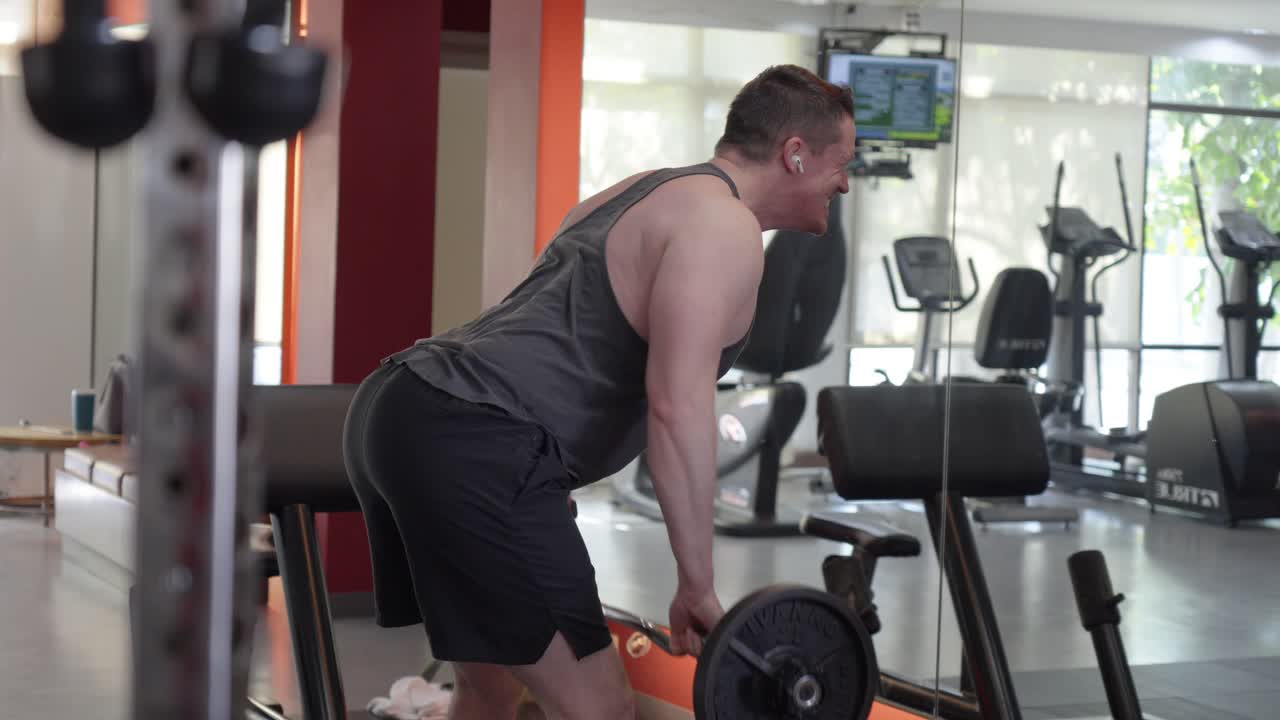 A man performing a barbell bent-over row in a gym. Focused on back and arm strength, this workout highlights the concept of weight training, muscle development, and physical fitness.