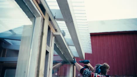 man at work assembling window frame with cordless electric drill