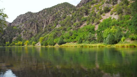 crystal-clear, emerald-like water flows through black canyon of the gunnison national park, colorado. surrounded by lush green trees, gentle waves ripple from a soft breeze, rocky landscapes.