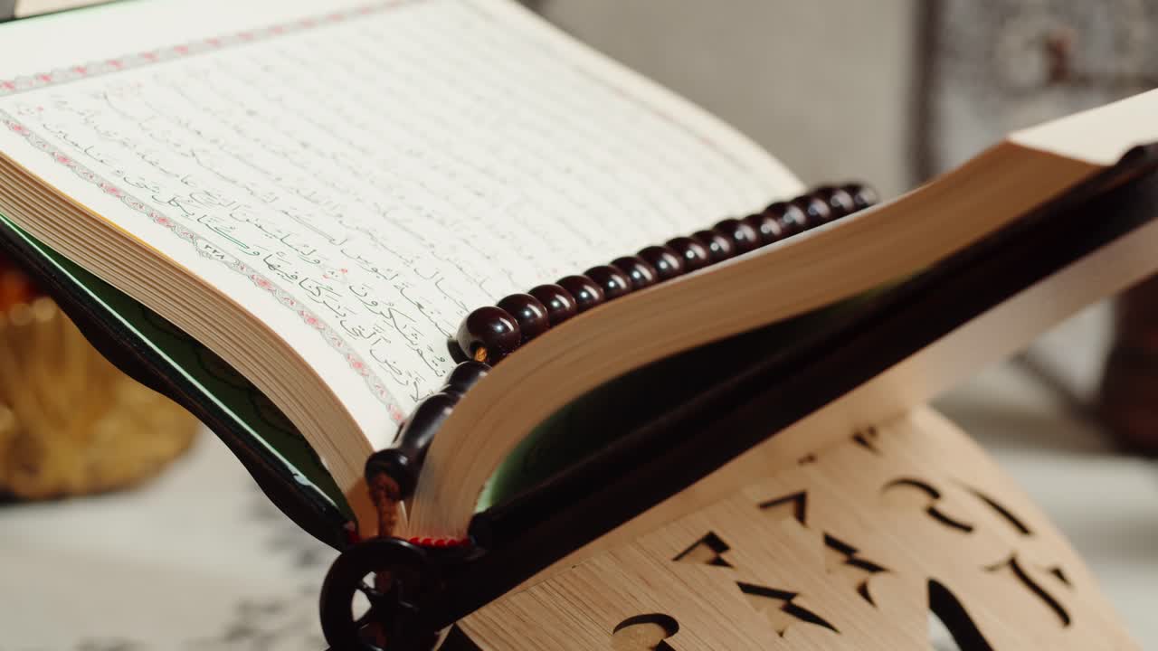 An open Quran on a wooden stand with prayer beads