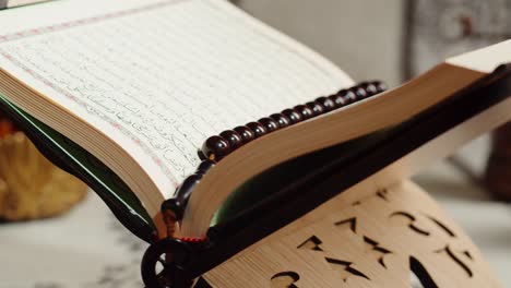an open quran on a wooden stand with prayer beads