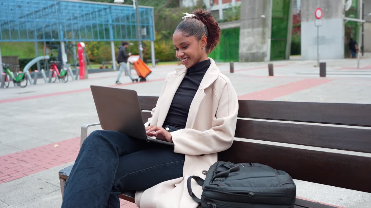 A woman sitting on a bench in a park using a laptop
