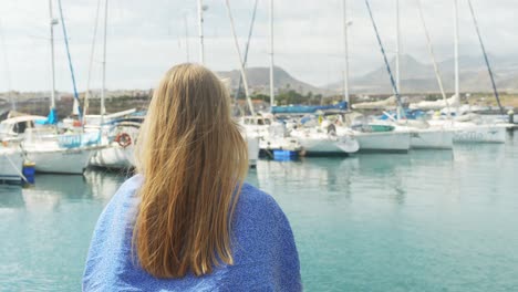 hermosa mujer rubia admira el muelle y el paisaje montañoso de tenerife, vista trasera