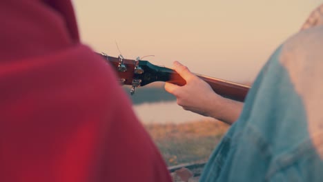 man-plays-guitar-with-tourists-on-steep-river-bank-backside