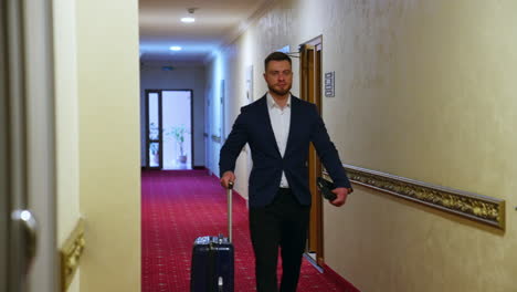 handsome business man walking at hotel corridor. young man with luggage arriving at hotel. tourist man settling in business hotel. slow motion.