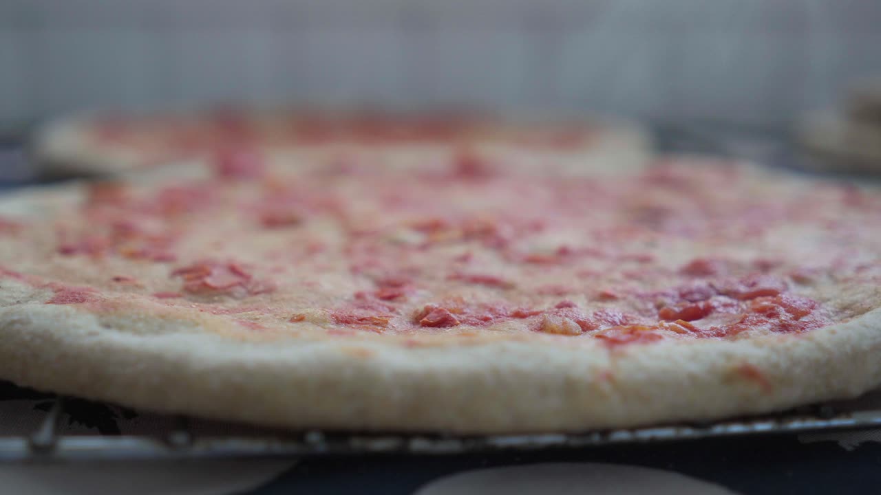 Nærbilde av en varm, hjemmelaget pizza rett ut av ovnen, klar for å legge på fyll og ferdigstille stekingen.