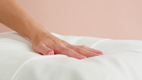la mano de una mujer tocando una almohada blanca