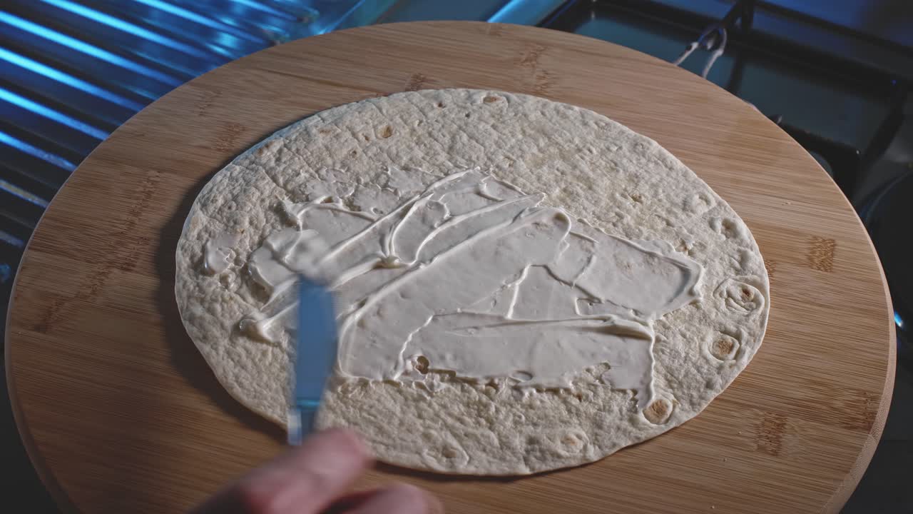 esparciendo mayonesa y salsa de tomate sobre la envoltura de tortilla, luego agregue el pollo y los huevos cocidos