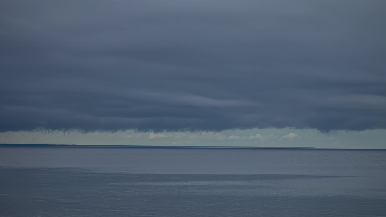 폭풍우 구름이 물 위에서 회색 하늘을 가로질러 이동하는 시간 경과