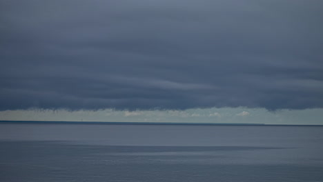 Timelapse-of-storm-clouds-moving-across-gray-sky-over-water-body