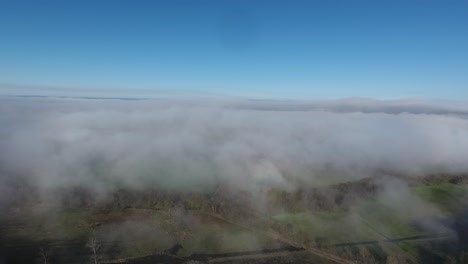 Drone-shot-moving-forward-over-clouds-in-south-of-France,-fields-and-vineyards-u