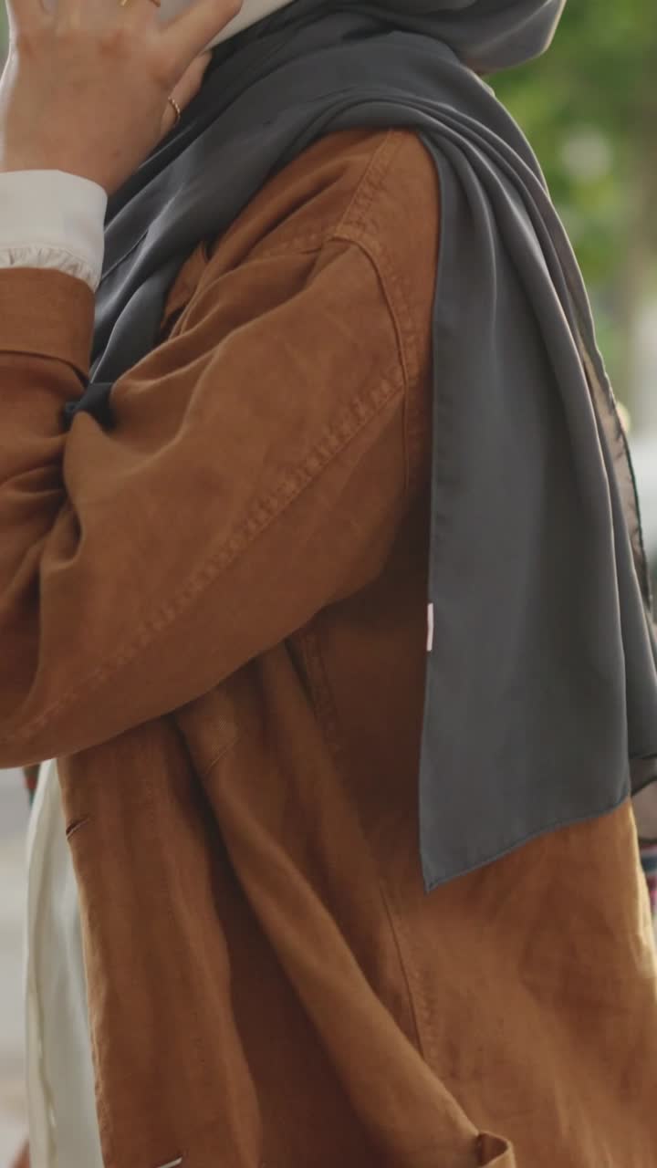 Una donna con hijab parla al suo smartphone all'aperto