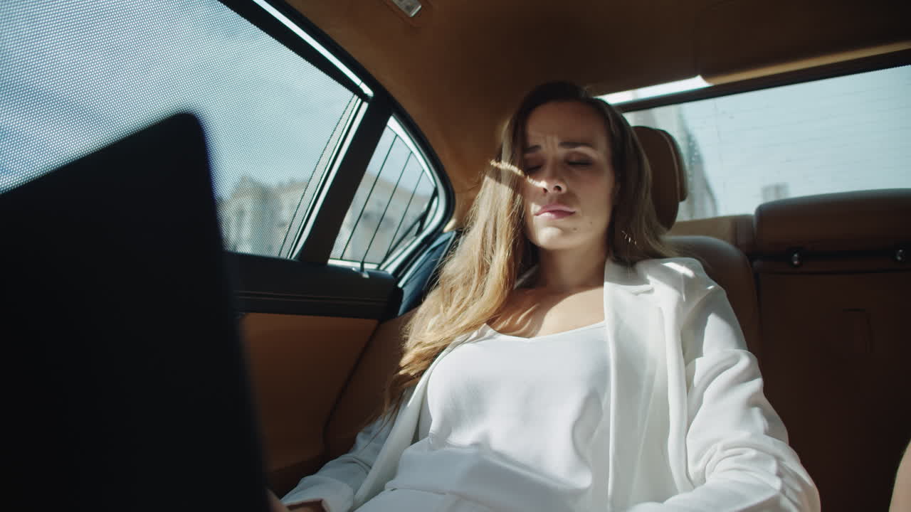 럭셔리 자동차에서 노트북으로 일하는 집중된 사업가의 초상화.