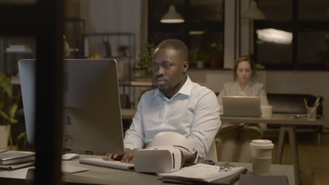 vista ravvicinata dell'uomo americano seduto alla scrivania in ufficio con occhiali per realtà virtuale