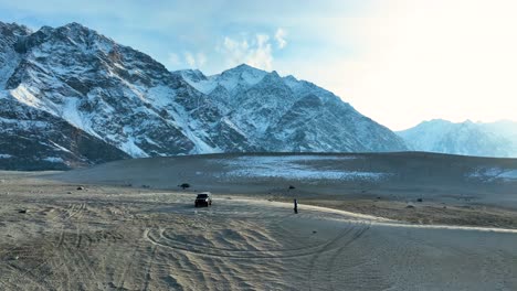 Geländewagen-Und-Person-In-Der-Kalten-Wüste-Sarfaranga-Mit-Schneebedeckten-Bergen-Im-Skardu-Tal