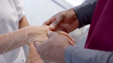vista de cerca de un médico afroamericano examinando la mano de una paciente caucásica en el hospital