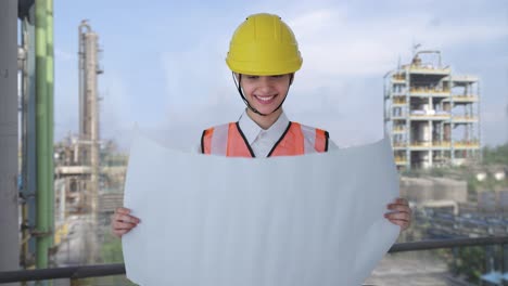 Happy-Indian-female-architect-looking-through-the-blueprint-of-house