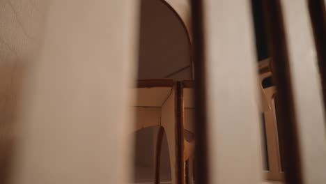 una muñeca pequeña se sienta en la mesa una persona pone una silla en la casa de juguetes