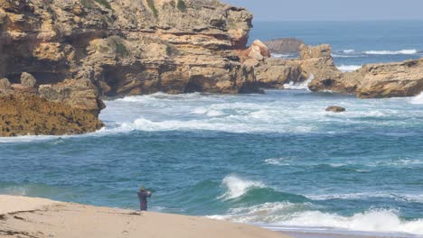 person fishing by rocky coastal waves