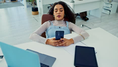 mujer trabajando en la oficina, apoyándose en el escritorio, descansando, usando el teléfono móvil