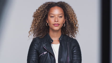 head and shoulders studio shot of woman wearing leather jacket looking at camera in slow motion