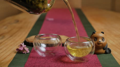 pouring tea into two small glass cups