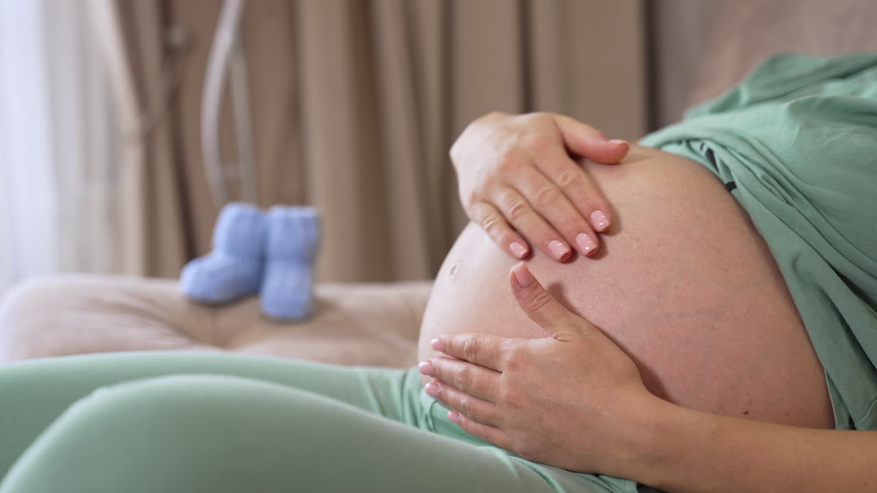 Donna incinta accarezza il pancione. Primo piano di donna incinta felice con il pancione a casa.