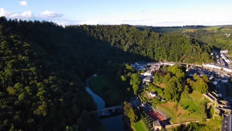 Aerial-view-of-the-Semois-River-flowing-through-the-Belgium-countryside-with-a-small-town-bordering-the-water