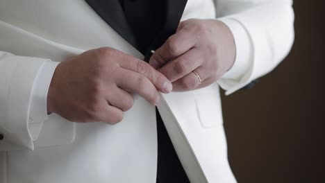 groom getting ready for wedding in white tuxedo