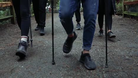 close-up shot van de voeten van een groep wandelaars, ze lopen dicht bij elkaar op een natuurlijk pad