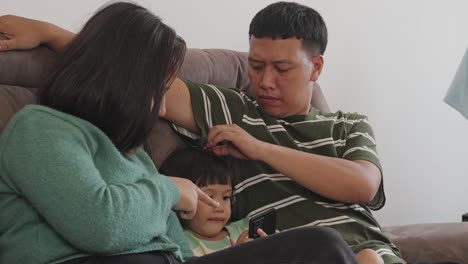 close up of a asian family spending time together, using smartphone while sitting on sofa at home