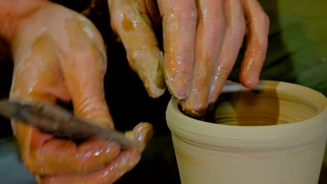 professional potter shaping mug with special tool in pottery workshop