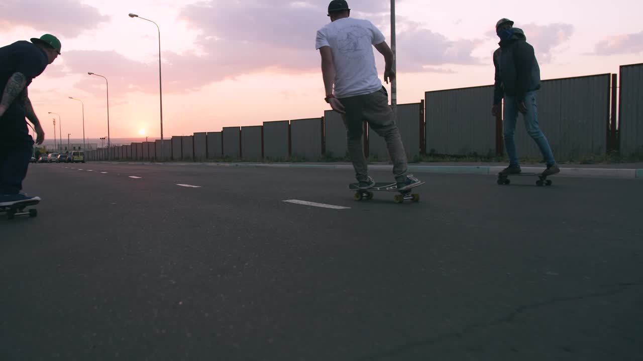Group of young people skateboarding on the road in the early morning, cinematic shot, slow motion