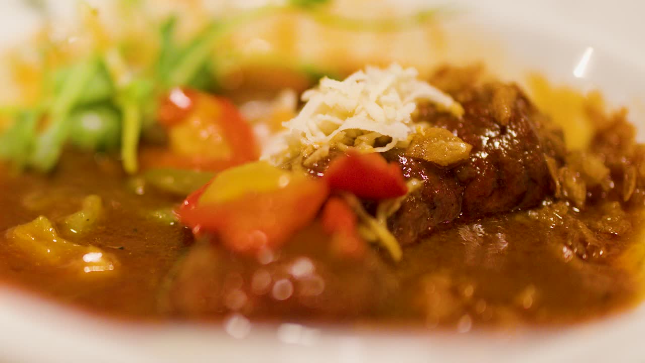 A spoon lifts hearty Czech goulash with vegetables and garnish in a warm restaurant setting
