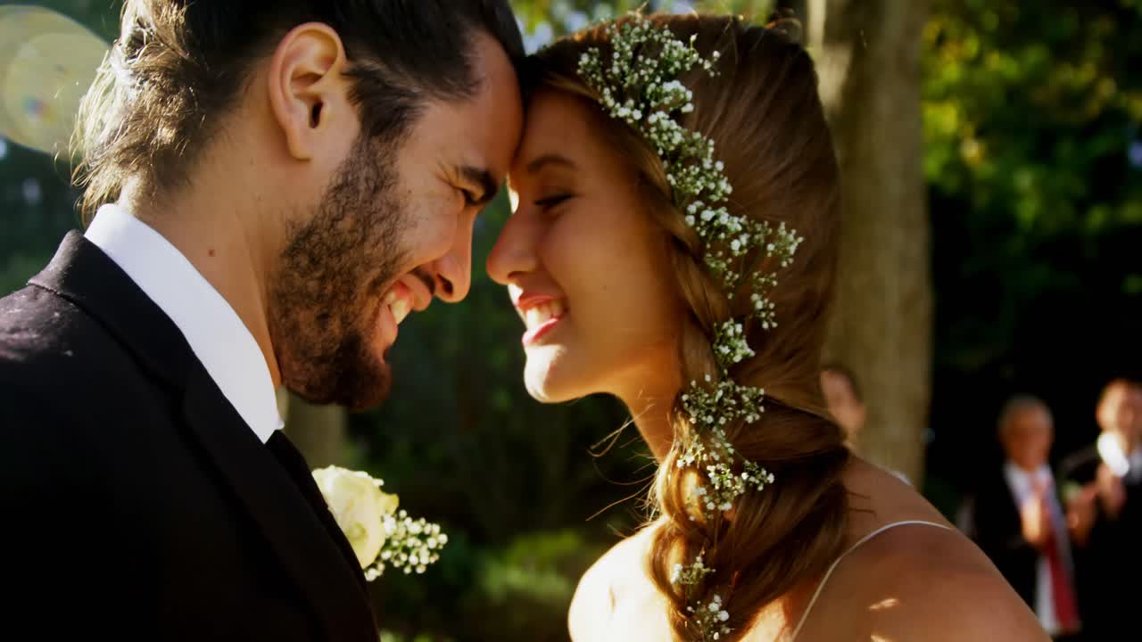 la novia y el novio abrazándose y los invitados aplaudiendo en el fondo 4k 4k